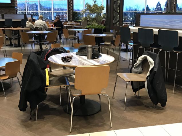 As people warm up, they leave their coats and hats on the food court chairs